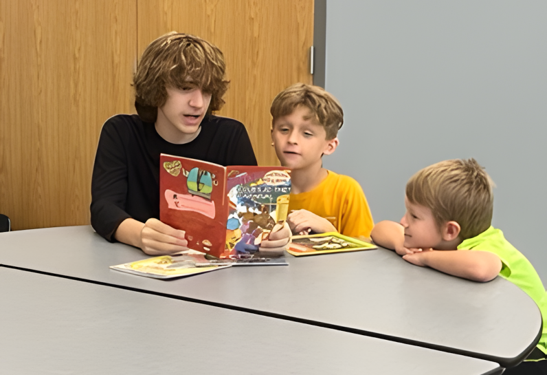 boy reading to two students